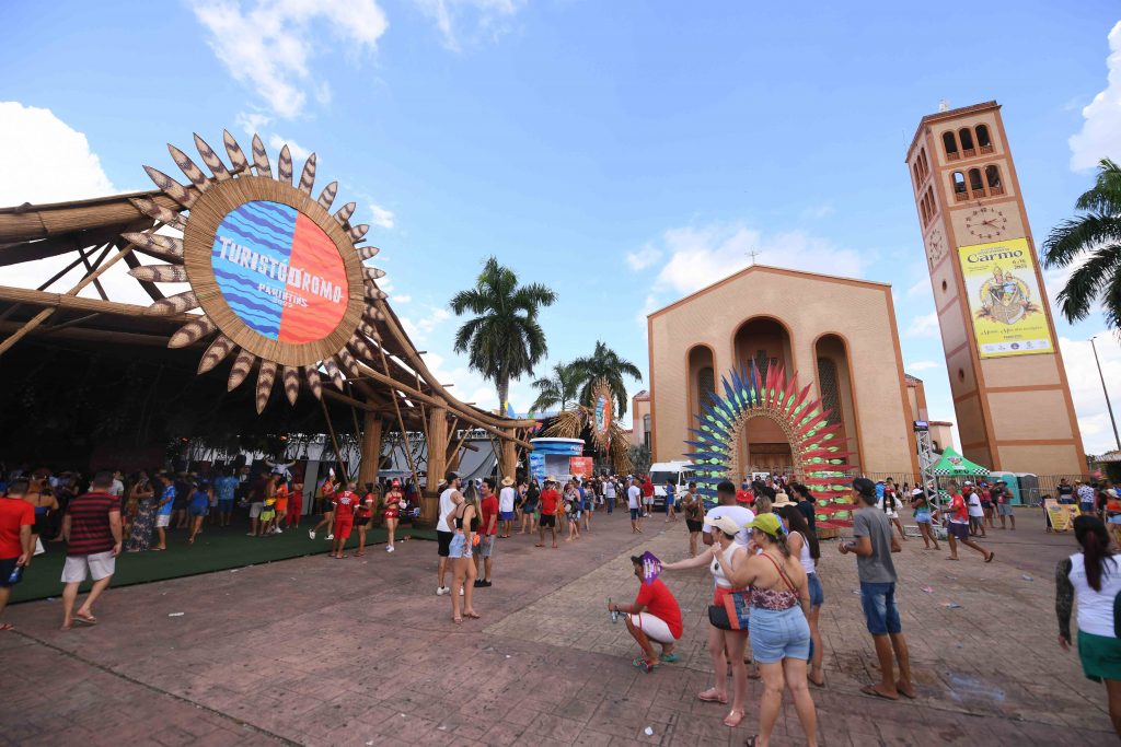 Visitantes passeiam de triciclo durante o Festival de Parintins 2024, com vista para o rio Amazonas