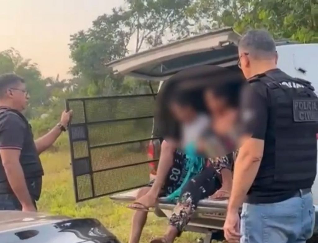 Policiais conduzindo casal preso por estupro de vulnerável de adolescente. Cena em comunidade na zona rural do Amazonas.
